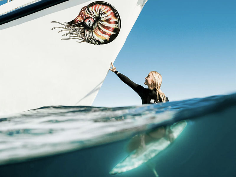 TROPIC ROVER girl on surfboard touching hull
